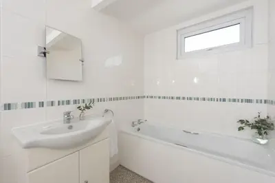 a white bathroom with a sink and a bath tub at Bridge Apartment - Free Parking & WiFi - Near Perranporth Beach in Perranporth