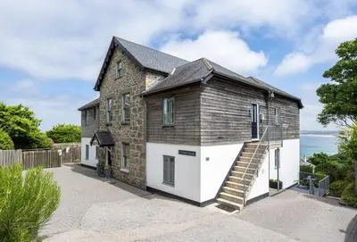 an old stone house with white doors and stairs at 8 Fernhill in Carbis Bay