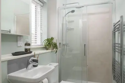 a white bathroom with a shower and a sink at Salt Life, Dunes at Upton Towans - Hot tub - Pet friendly - Self check in in Hayle