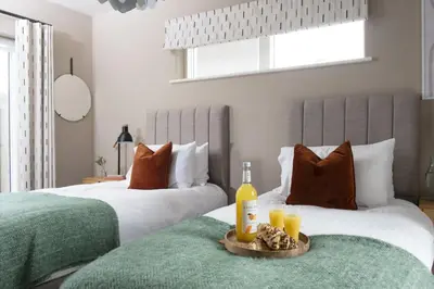 two beds in a bedroom with a tray of food and drinks at Salt Life, Dunes at Upton Towans - Hot tub - Pet friendly - Self check in in Hayle
