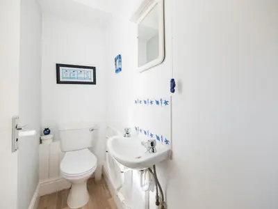 a white bathroom with a toilet and a sink at Pinewood Flat 5 in Polzeath