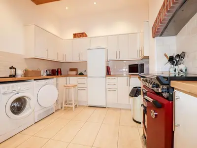 a kitchen with white cabinets and a washer and dryer at Lewarne in Boscastle