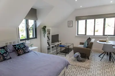 a bedroom with a bed and a living room at Valley View Studio Annexe in Downderry