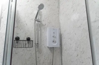 a shower with a shower head in a bathroom at Valley View Studio Annexe in Downderry
