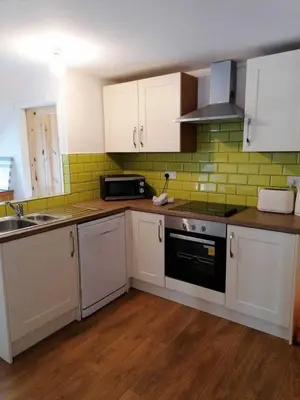 a kitchen with white cabinets and a black stove top oven at Nice big 2 double bedroom Apartment in the Town in Newquay
