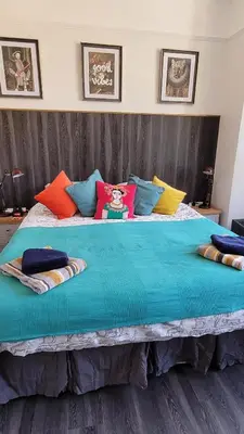 a large bed with colorful pillows on it at Lansdowne Simply Stay in Redruth