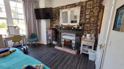a bedroom with a fireplace and a bed and a mirror at Lansdowne Simply Stay in Redruth