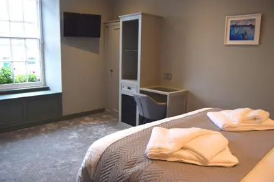a bedroom with a bed and a desk and a window at Crown Inn in Penzance