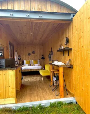 a large wooden room with a bed and a table at Trethowels Hidden Huts in St Austell