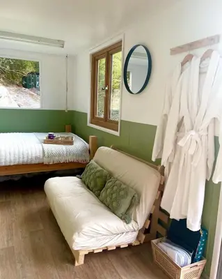 a room with two beds and a couch and a mirror at Trethowels Hidden Huts in St Austell