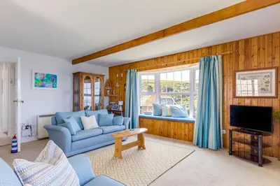 a living room with a blue couch and a tv at Gulland in Port Isaac