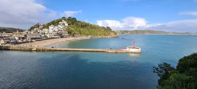 a boat in the water next to a beach at Cosy Bake Cottage, Great Location in Looe, Cornwall in Looe