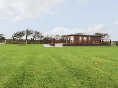 a large grass field with a building in the background at Sycamore Lodge in Helston