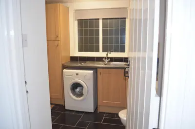 a bathroom with a washing machine and a sink at The Cottage, Treliggon Farm in Lanivet