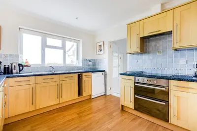 a kitchen with wooden cabinets and blue tiles at Trebartha in Polzeath
