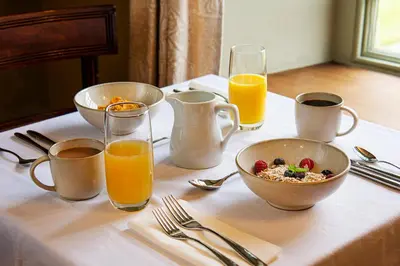 a table with a bowl of cereal and glasses of orange juice at Cusgarne Manor boutique B&B - adults only in Cusgarne