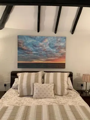 a bedroom with a bed with a painting on the wall at The Cottage Bed & Breakfast in Polperro
