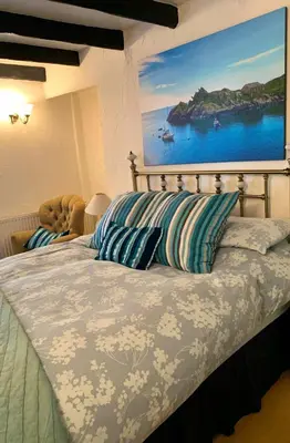 a bedroom with a bed with a painting on the wall at The Cottage Bed & Breakfast in Polperro