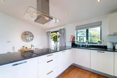 a kitchen with white cabinets and black counter tops at Porthminster Mews in St Ives