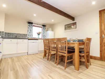 a kitchen with a wooden table and chairs at The KilnsThe West Dry in St Austell
