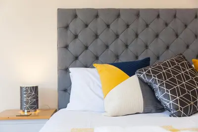 a bed with a gray headboard and pillows on it at The KilnsThe West Dry in St Austell