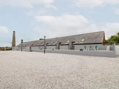 a barn with a white fence and a building at The LinneyThe West Dry in St Austell