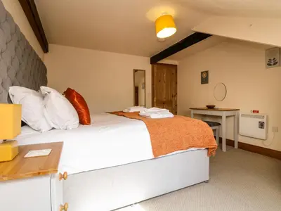 a bedroom with a large bed and a desk at RiversideThe West Dry in St Austell