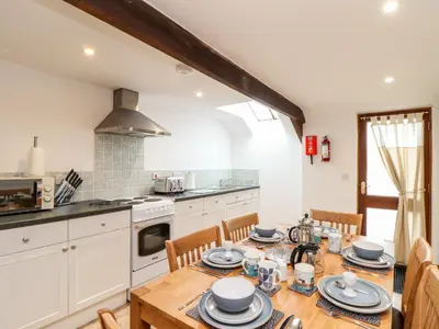 a kitchen with a wooden table with plates and dishes on it at RiversideThe West Dry in St Austell