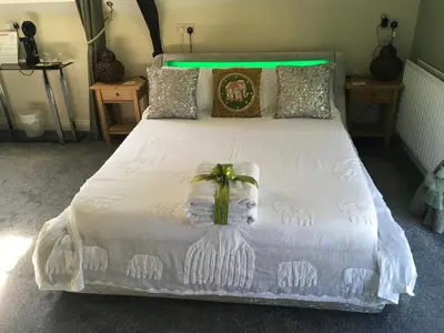 a bedroom with a white bed with a bow on it at Cherrywood Lodge in Looe