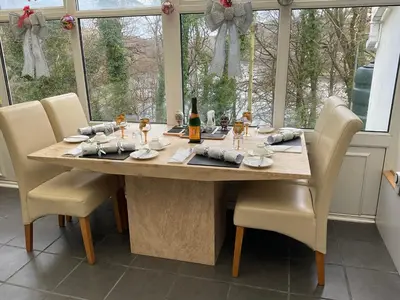 a dining room table with chairs and a bottle of wine at Cherrywood Lodge in Looe