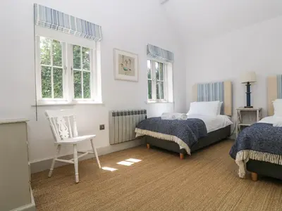 a bedroom with two beds and a chair at Wood Meadow in Helston
