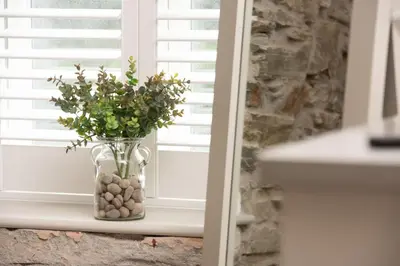 a vase filled with rocks and flowers in a window at Beach Cottage in St. Agnes