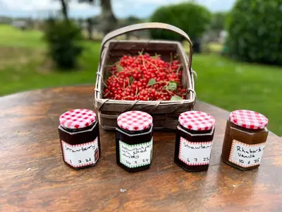 a basket of strawberries sitting on a table with jam jars at Charming Guest House in Cornish Countryside in Bodmin