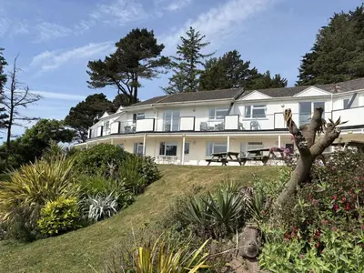 a large white house with a garden in front of it at View of the Sea - Mount Brioni in Downderry
