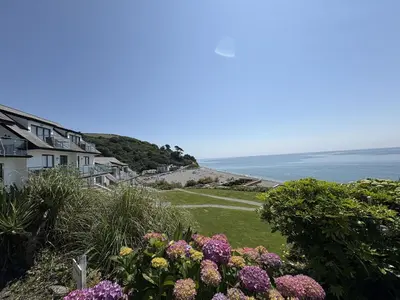 a view of the ocean from a house with flowers at Sea Gem - Mount Brioni in Downderry