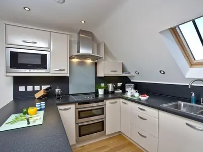 a kitchen with white cabinets and a sink at Lowena - Mount Brioni in Downderry