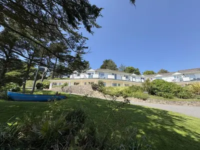 a house with a blue boat in the grass at Surf Watch - Mount Brioni in Downderry