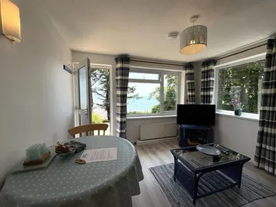 a living room with a table and a tv at Sea Breeze - Mount Brioni in Downderry