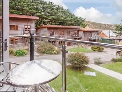 a balcony with a table and a view of a yard at Coppercroft Cottage - Stunning Coastal Home, Walk to Beach, Sleeps 4 in Porthtowan