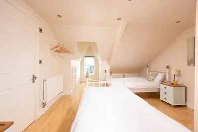 a white bedroom with two beds and a window at Windsor Lookout in St Ives