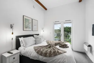 a white bedroom with a large bed and a window at Silvercroft Cottage - Luxury Modern Coastal Retreat Near Beach, Sleeps 4 in Porthtowan