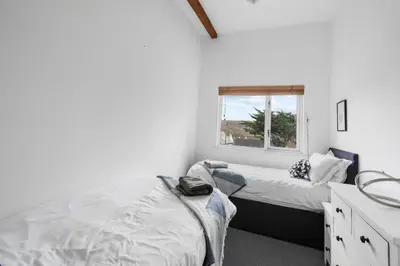 a bedroom with two beds and a window at Silvercroft Cottage - Luxury Modern Coastal Retreat Near Beach, Sleeps 4 in Porthtowan