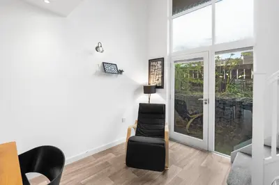 a living room with a chair and a window at Silvercroft Cottage - Luxury Modern Coastal Retreat Near Beach, Sleeps 4 in Porthtowan