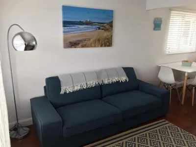 a living room with a blue couch and a table at Holiday Chalet at Gwithian Sands in Cornwall in Gwithian