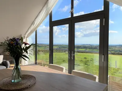 a dining room with a table and a large window at The Neyth in Budock Water