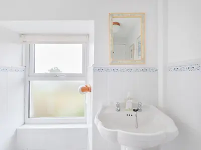 a white bathroom with a sink and a window at Finest Retreats - West Cottage at Goldsithney in Perranuthnoe