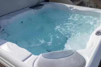 a bath tub with blue water in it at Herons House Sleeps 12, heated Pool, hot tub, sauna, games room 5 Star! in Saint Columb Major
