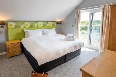 a bedroom with a large bed and a large window at PointBreak Sleeps 12 with hot tub-Great celebration house-Dog friendly in Padstow