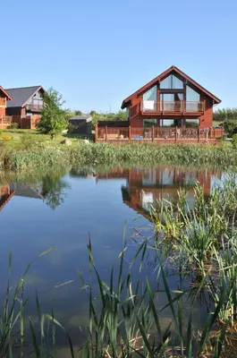 a house with a lake in front of it at Swallow Lodge with Hot Tub, dogs welcome sleeps 8, Great resort Facilities in Padstow