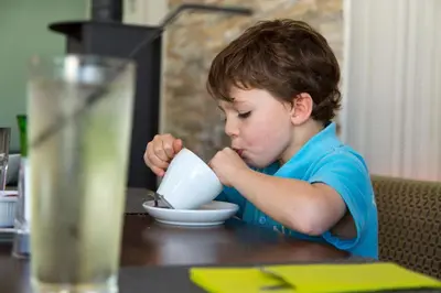 a young boy sitting at a table drinking from a bowl at Swallow Lodge with Hot Tub, dogs welcome sleeps 8, Great resort Facilities in Padstow